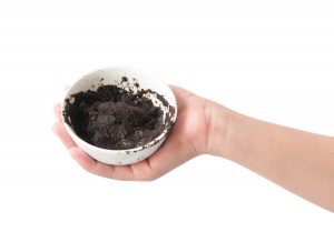Woman's hand holding bowl of coffee grounds for skin scrub health care and beauty concept
